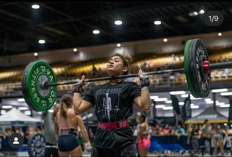 Woman driving a loaded barbell overhead during a weightlifting competition