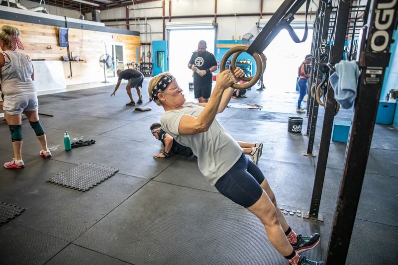 Athlete pulling herself up on gymnastics rings during a coach-led CrossFit class